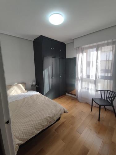 a bedroom with a bed and a chair and a window at Sagasti in Astigarraga