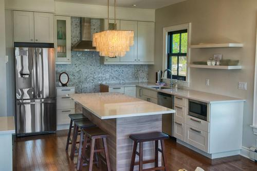 a kitchen with white cabinets and a island with bar stools at Dunlop Inn in Baddeck