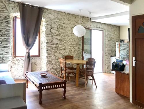 un salon avec une table et un mur en pierre dans l'établissement LA MINORQUIN appartement avec terrasse, à Port-Vendres