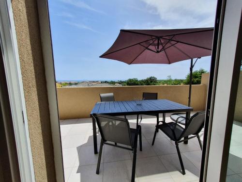 a balcony with a table and chairs and an umbrella at Casa di lise e bastien in San-Nicolao