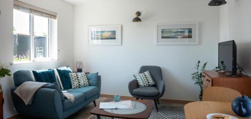 a living room with a blue couch and a chair at Furlong Cottage @ Higher Stancombe Farm in Kingsbridge