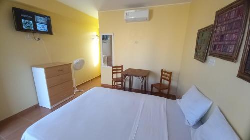 a bedroom with a white bed and a table and chairs at Hospedaje Ola Marina in Máncora