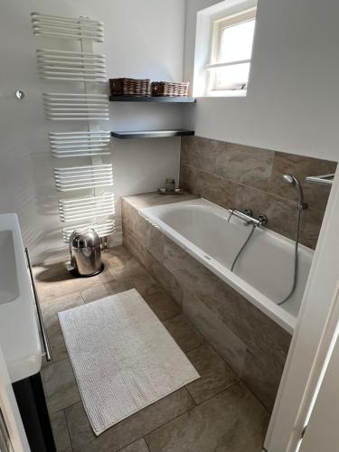 a bathroom with a bath tub and a window at Strandvilla Juliana in Julianadorp