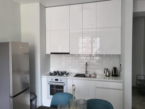 a white kitchen with white cabinets and blue chairs at New stylish 2 bedroom - Apartment in New building in Tbilisi City