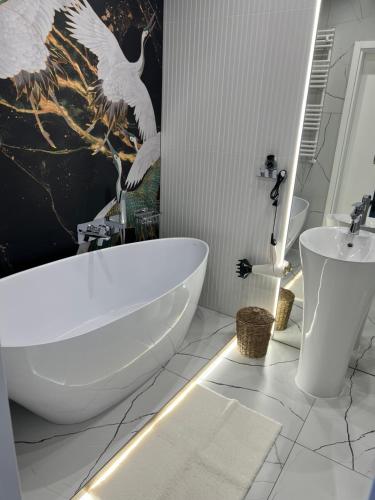 W łazience znajduje się biała wanna i tapeta z ptakami. w obiekcie Apartament Przystań Iława Green w Iławie