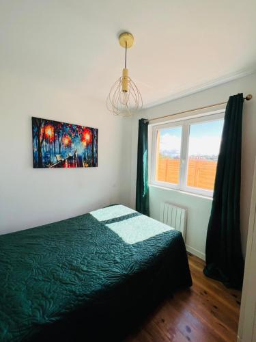 une chambre avec un lit vert et une fenêtre dans l'établissement Les Dryades proche de la Mer, à Sainte-Marguerite