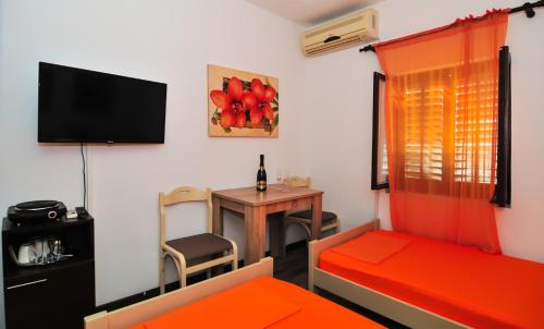 a room with a bed and a table with a television at Sofia Rooms in Tivat