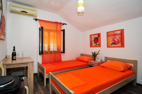 two beds in a room with orange sheets at Sofia Rooms in Tivat