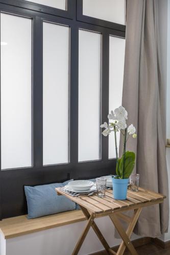 une table avec un vase de fleurs sur une table devant les fenêtres dans l'établissement L'Orchidée : Studio proche RER B - Cachan, à Cachan