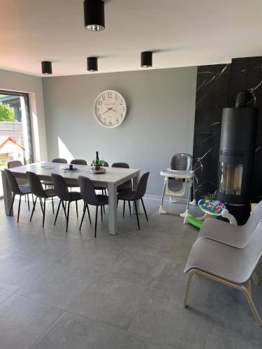 a dining room with a table and chairs and a clock at Apartament Nadziei in Chmielno