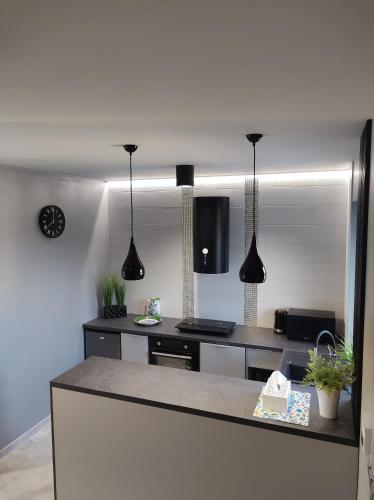 a kitchen with black pendant lights and a counter at Apartament Nadziei in Chmielno