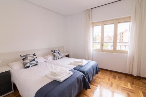 Un dormitorio con dos camas y una ventana. en Apartamentos El Balcón del Duero, en San Esteban de Gormaz