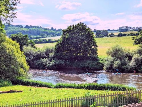 a river in the middle of a field with a fence at Worralls Grove Guest Farm House in Bewdley