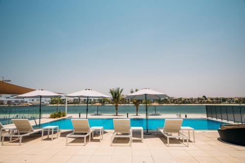 una piscina con sillas, mesas y sombrillas en Family vacation villa with private pool and access to beach, en Ras al Khaimah