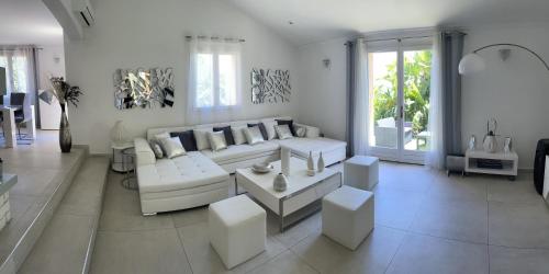 a white living room with a couch and a table at VILLA LES YUCCAS - Pool - Sea view in Cagnes-sur-Mer