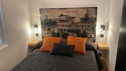 een slaapkamer met een bed met oranje kussens en een schilderij bij Apartamento Grace in Sintra