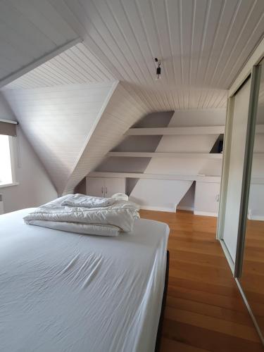 Cama blanca en habitación con ático en Stijlvolle vakantiewoning Den Baigneur aan zee, en Knokke-Heist