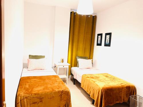Cette chambre comprend 2 lits avec des draps orange. dans l'établissement Apartamento Rincón, Ideal para familias, à Cala del Moral