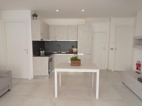 a white kitchen with a table and a sink at Gelsimori Apartments in Otranto