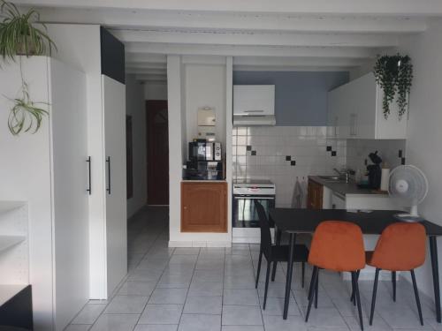 una cocina con mesa negra y sillas naranjas en Studio tout confort centre ville - Balcon, Clim, TV, Wifi, en Mazan