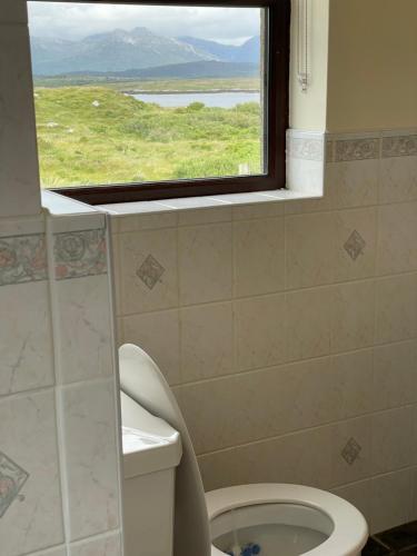 a bathroom with a window and a toilet with a view at Cill Cottage in Roundstone