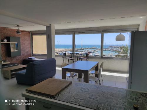 - un salon avec une table et une vue sur l'océan dans l'établissement Appartement vue mer, à Narbonne-Plage