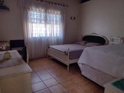 Casa no centro em Garopaba في غاروبابا: غرفة نوم بها سريرين ونافذة