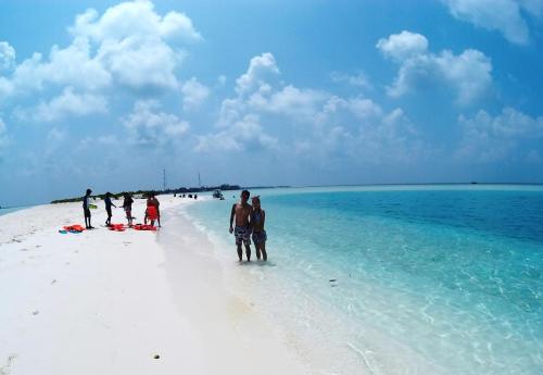 a group of people standing on a white beach at Rasdhoo Coralville in Rasdu