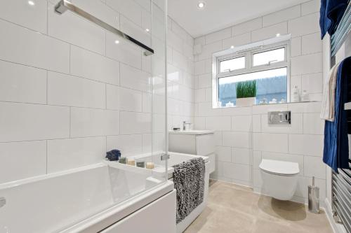 a white bathroom with a tub and a toilet at Butterfly House - Luxury 2 Bedroom Property in Kettering