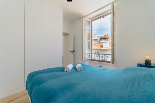 a bedroom with a blue bed and a window at Bakara, élégant t2 au cœur des Halles de Biarritz in Biarritz