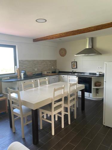 a kitchen with a white table and chairs in it at Casa dos Avós in Póvoa de Lanhoso