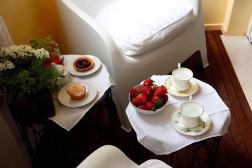 two tables with food and cups and a bowl of strawberries at Nest House & Relax in Civitanova Marche