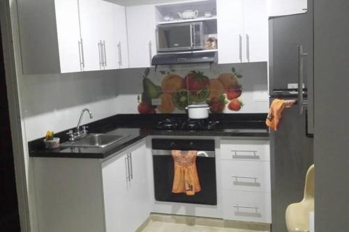 eine Küche mit weißen Schränken und einem Herd mit Backofen in der Unterkunft Fantástica cartagena accesible para todos in Cartagena de Indias