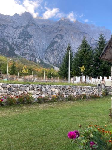 a stone wall in a yard with mountains in the background at Kulla e Sadri Lukes in Theth