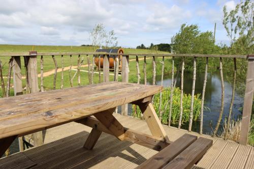 a wooden bench sitting on a deck next to a body of water at Shepherd's Loch Glamping in Turriff