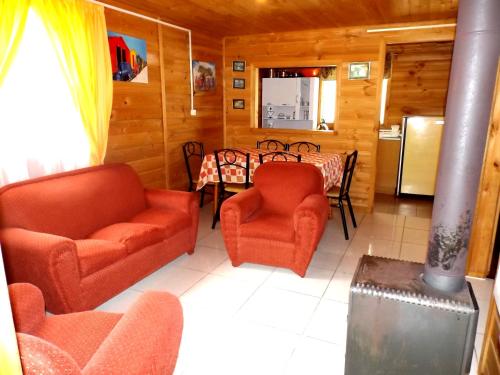a living room with a table and chairs and a kitchen at Cabañas Aguas Claras in Pinto