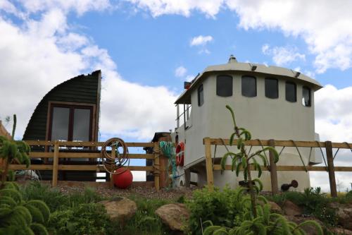 a house with a lighthouse next to a fence at Shepherd's Loch Glamping in Turriff