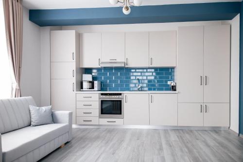 a kitchen with white cabinets and a couch at BlueSky Premium Apartment Baile Felix in Baile Felix