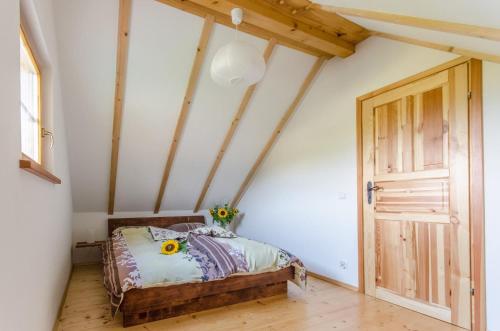 een slaapkamer met een bed en een houten deur bij Domki Pod Dębem 