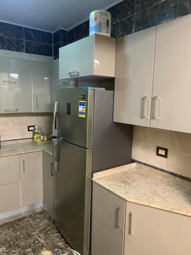 a kitchen with a stainless steel refrigerator and white cabinets at Paris st in Ismailia
