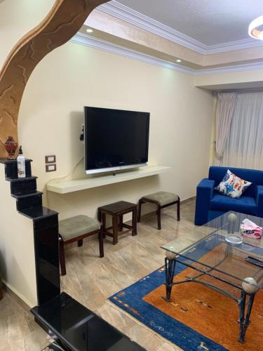 a living room with a blue couch and a flat screen tv at Paris st in Ismailia