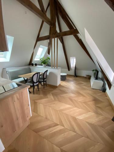 an attic room with a wooden floor and a table and chairs at Studio centre ville in Dol-de-Bretagne