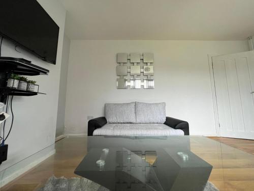 a living room with a couch and a glass table at Cosy home near NEC, BHX Bullring & Solihull in Birmingham