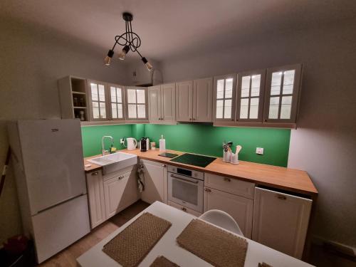 a kitchen with white cabinets and green walls at Komfortowy apartament przy lesie in Wejherowo