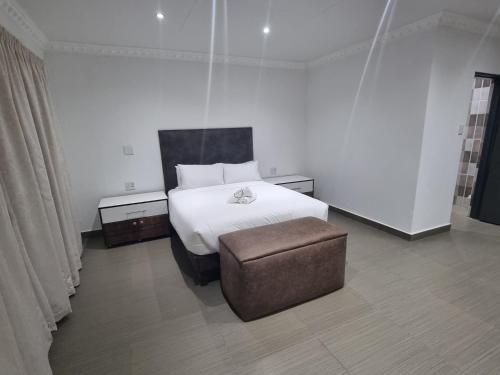 1 dormitorio con 1 cama con reposapiés y 1 silla en La Gracia lodge Nzhelele, en Nzhelele