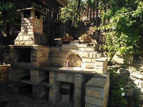 a stone fireplace in a yard with a sink at Къща за гости УЮТ с. Жеравна in Zheravna