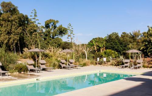 a swimming pool with lounge chairs and umbrellas at Luna Minoica Suites and Apartments in Montallegro