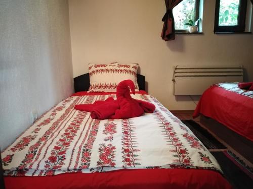 a stuffed red teddy bear laying on a bed at Къща за гости УЮТ с. Жеравна in Zheravna