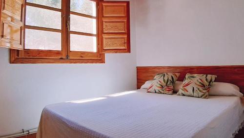 ein kleines Schlafzimmer mit einem Bett mit Fenster in der Unterkunft Casitas La Purísima Macho in Requena