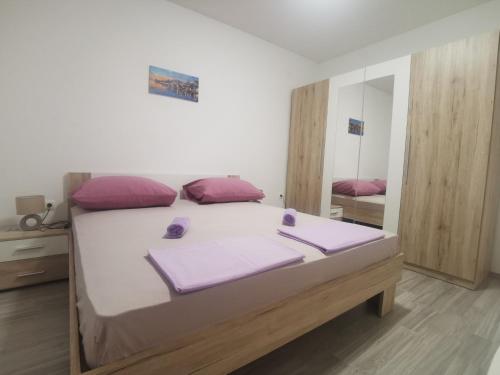 een slaapkamer met een bed met paarse kussens en een spiegel bij Apartman Dany in Kaštela